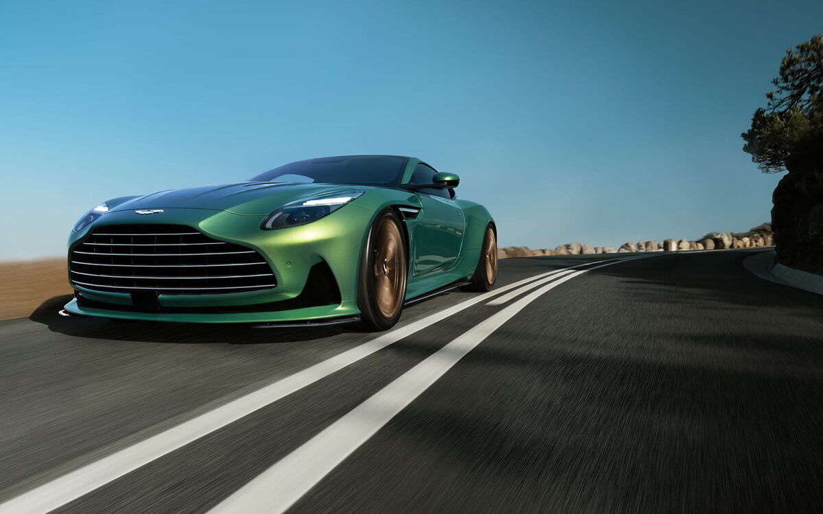 Green Aston Martin DB12 driving on a mountain road, front three-quarter view