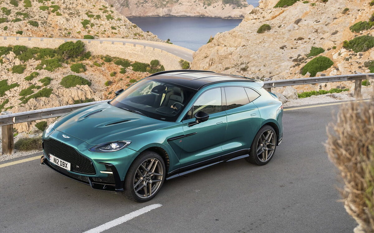 Teal Aston Martin DBX S on a coastal road, front three-quarter view