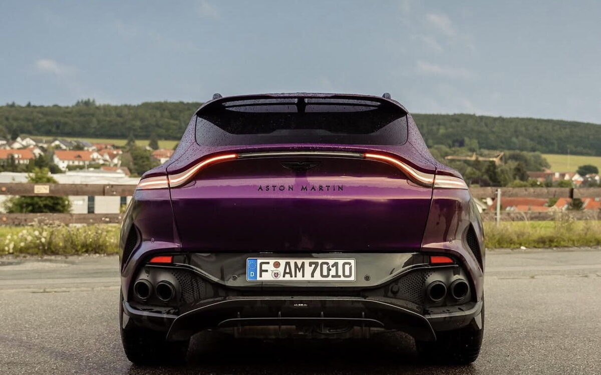 Purple Aston Martin DBX707 seen from behind in an open field