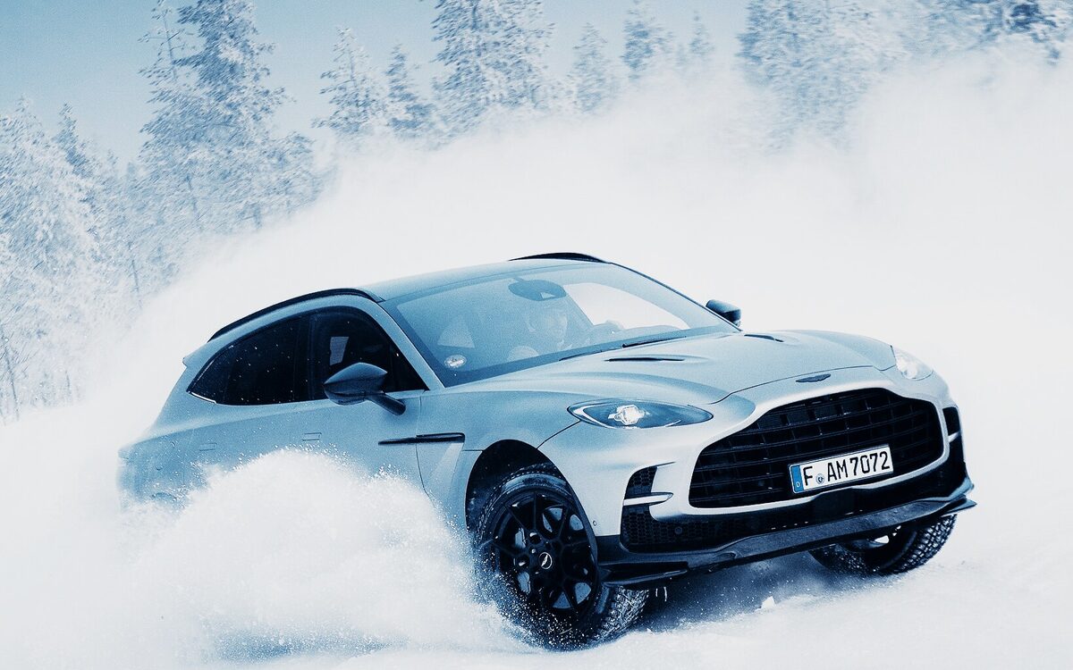 Silver Aston Martin DBX707 kicking up snow on a winter drive