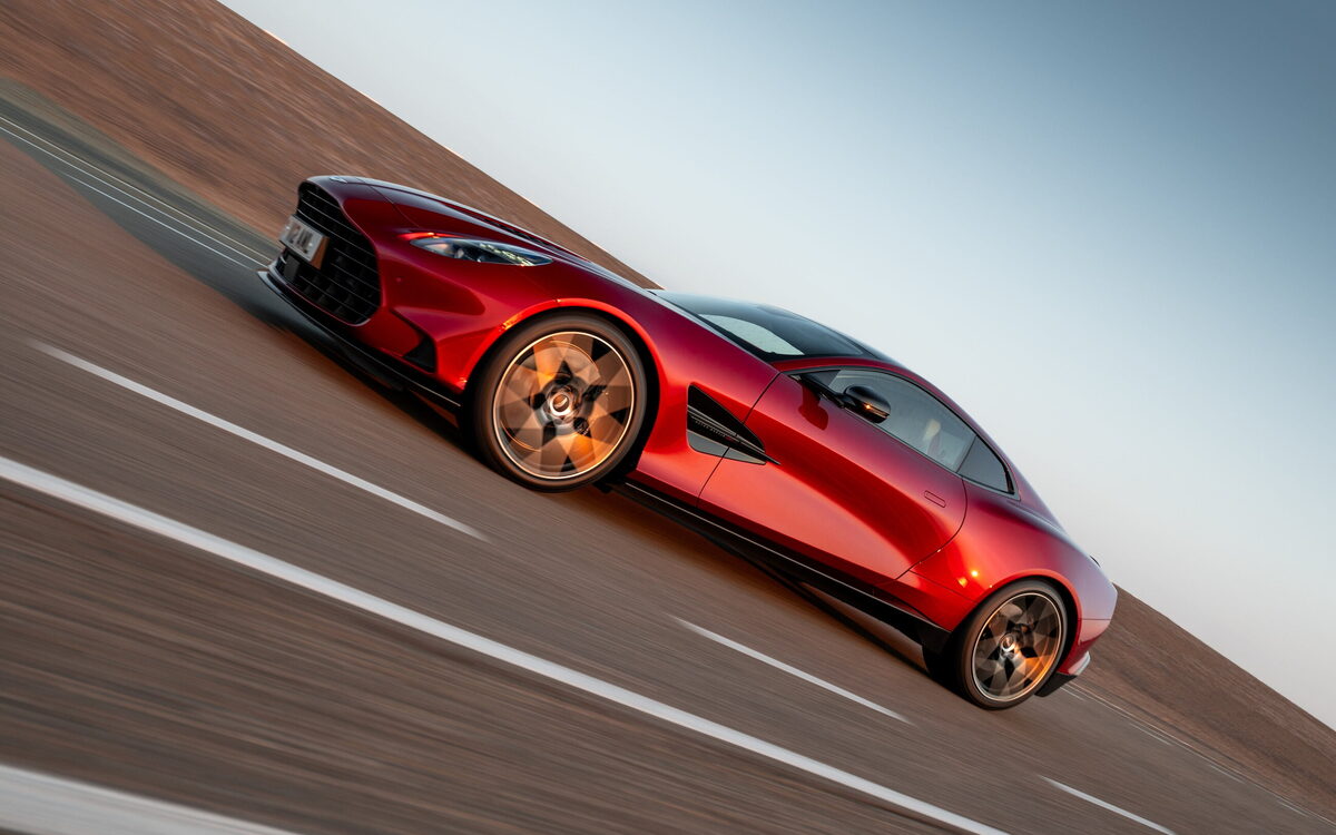 Red Aston Martin Vanquish climbing a hill road at speed, front three-quarter view