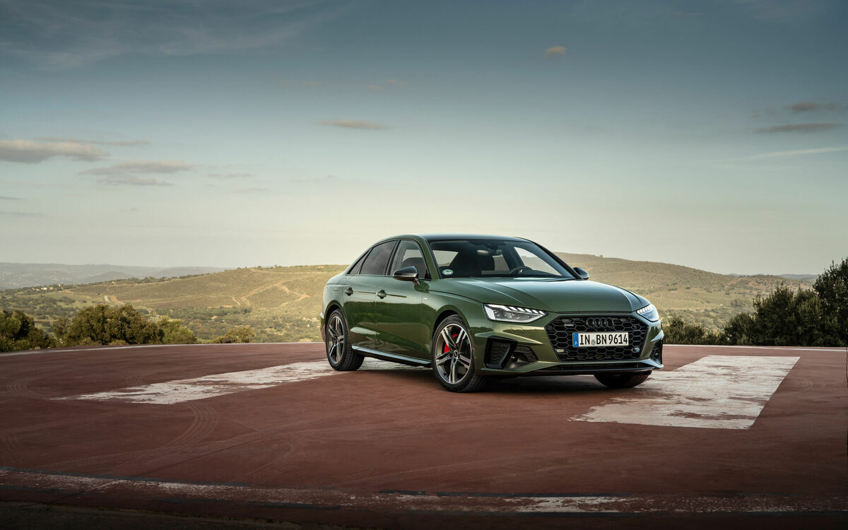 Audi A4 in District Green, front three-quarter view on a hilltop pad