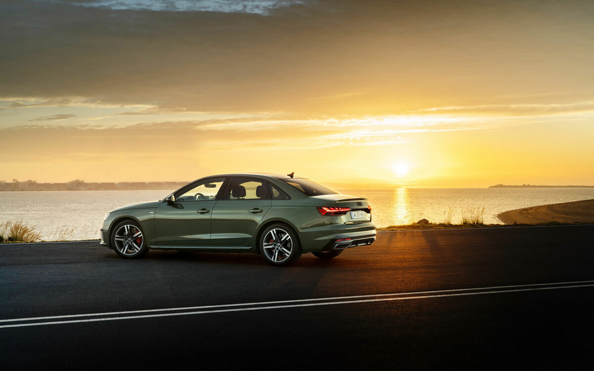 Audi A4 in District Green in side view against a sunset over the water
