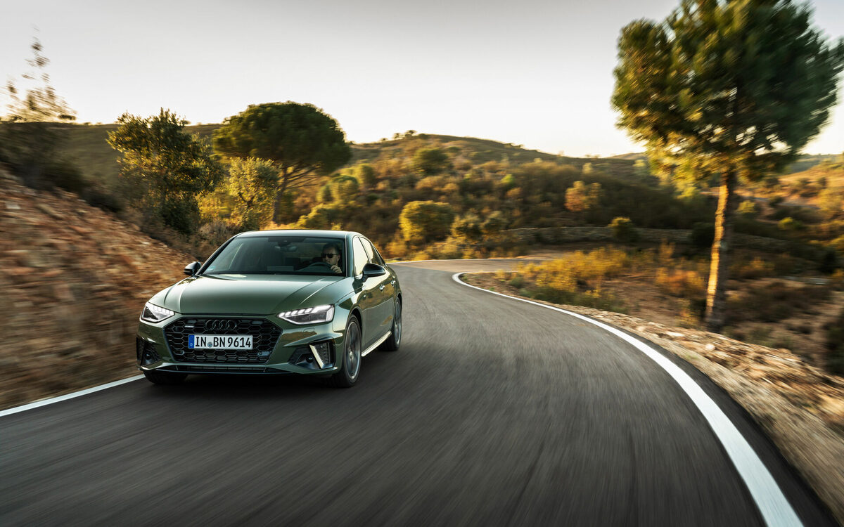 Audi A4 in District Green driving on a winding road, front view in motion