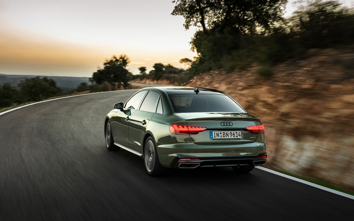 Audi A4 in District Green driving on a winding road, rear view in motion