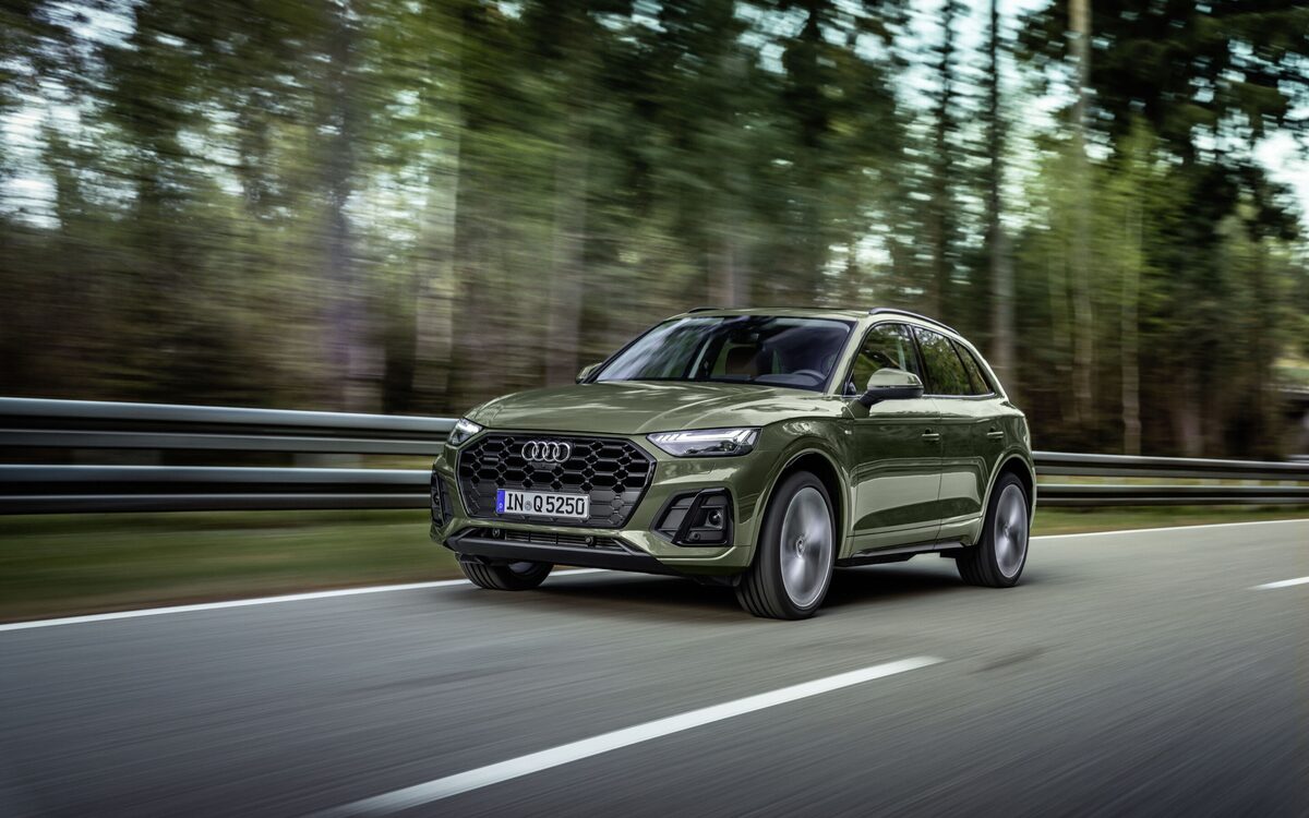 Audi Q5 in District Green, front three-quarter view driving fast along a forest road