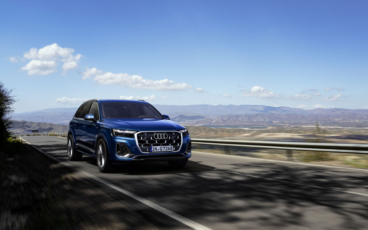 Audi Q7 in Ascari Blue driving along a road, front three-quarter view in motion