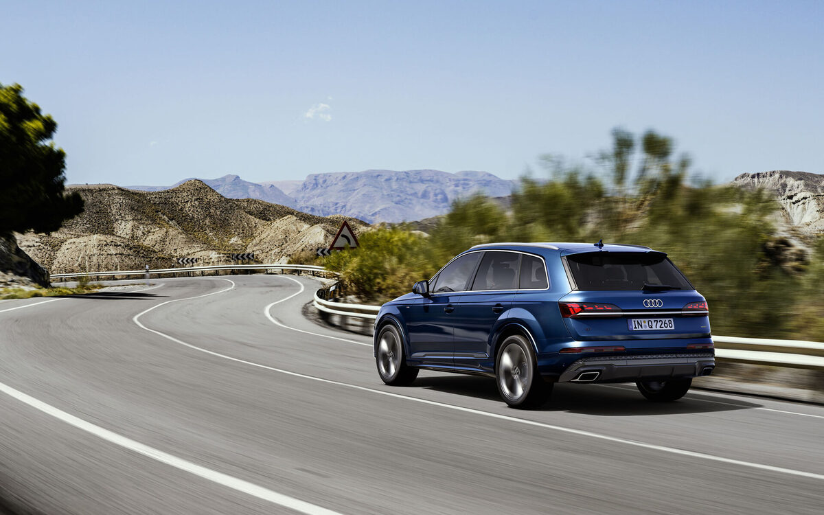 Audi Q7 in Ascari Blue driving on a road, rear three-quarter view