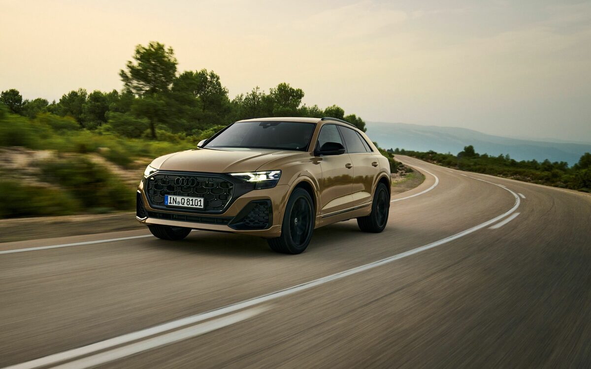 Audi Q8 in Sakhir Gold, front three-quarter view cornering on a curving country road