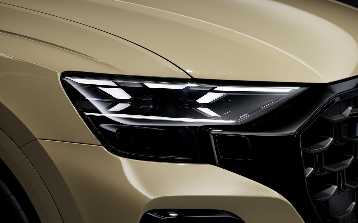 Audi Q8 in Sakhir Gold, close-up of the LED matrix headlamp and black grille edge