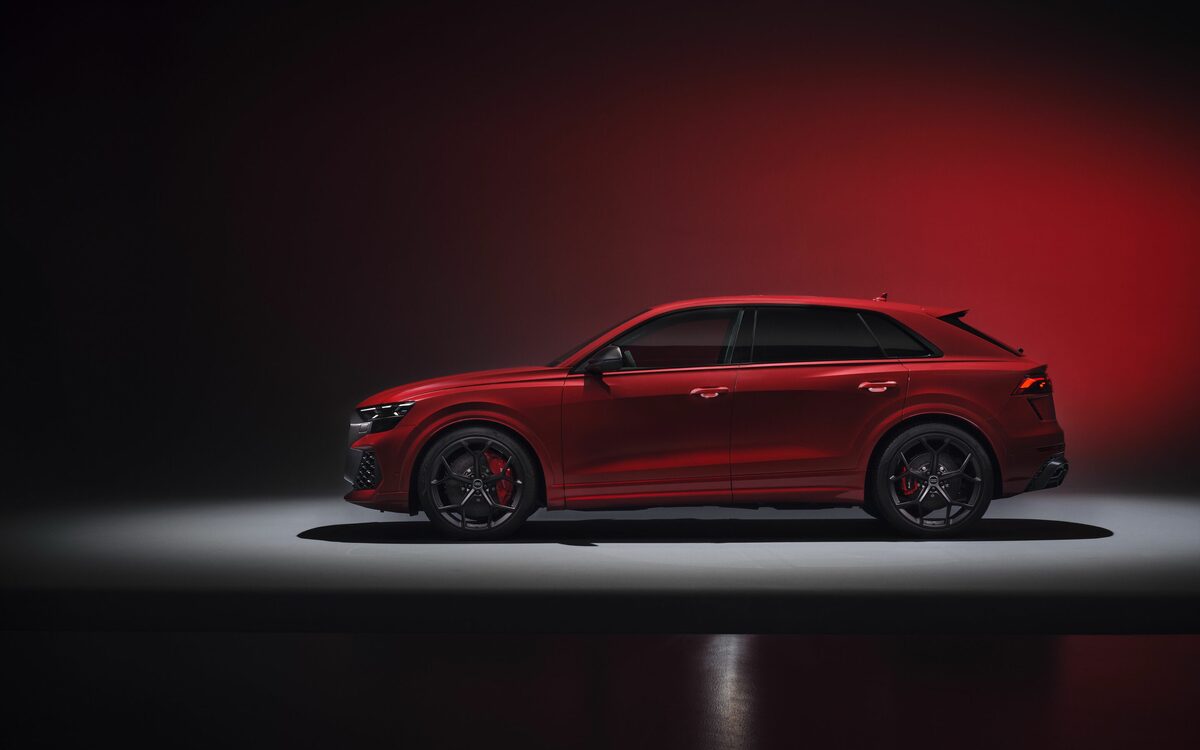 Audi RS Q8 performance in Chili Red, side profile in a dark studio with red backdrop