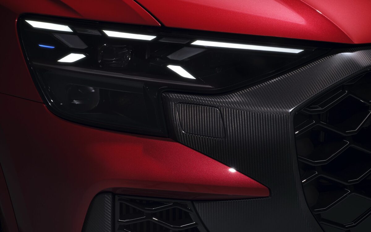 Audi RS Q8 performance in Chili Red, close-up of the LED headlamp and carbon-fibre grille surround