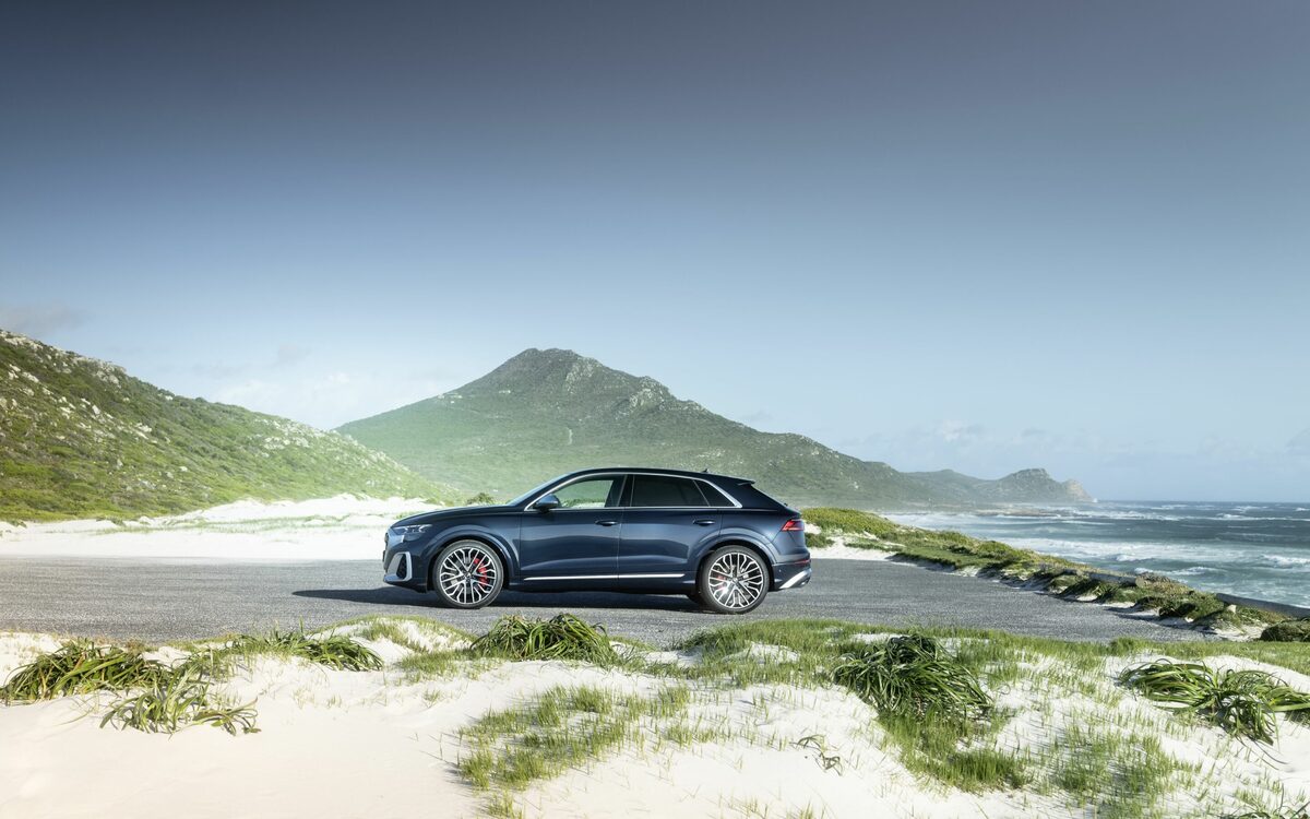 Audi SQ8 in Waitomo Blue, side profile parked among white dunes beside the sea