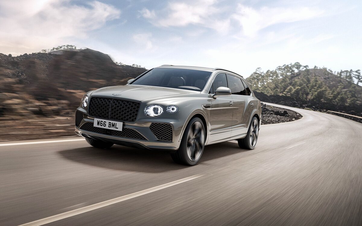 Bentley Bentayga in grey-gold, front three-quarter view on a mountain road