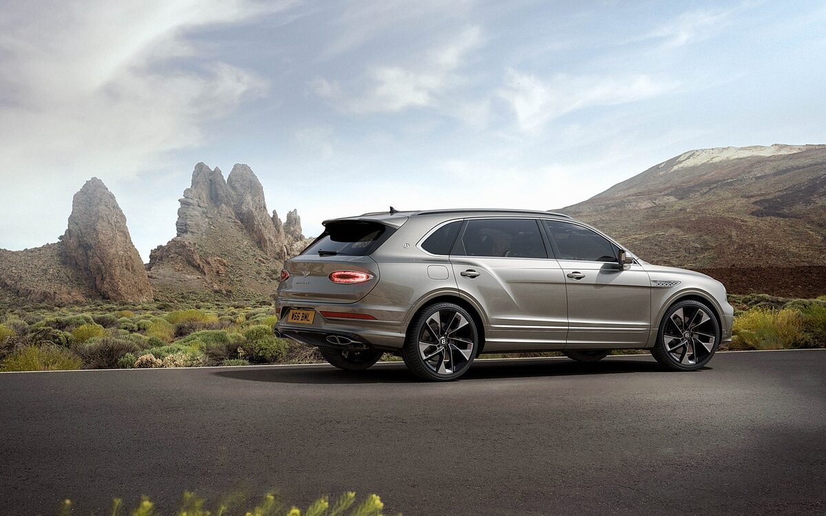 Bentley Bentayga, rear three-quarter view parked on a road in front of rock formations