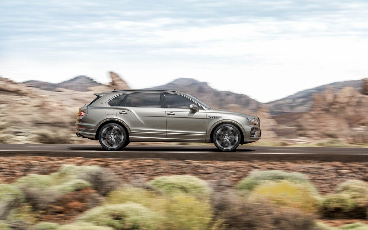 Bentley Bentayga in side profile driving past desert scrub