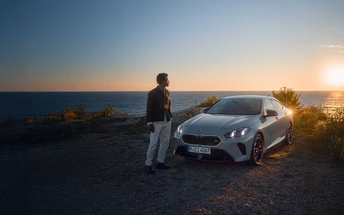 BMW 2 Series Gran Coupe parked on a coastal cliff at sunset with its owner standing beside it