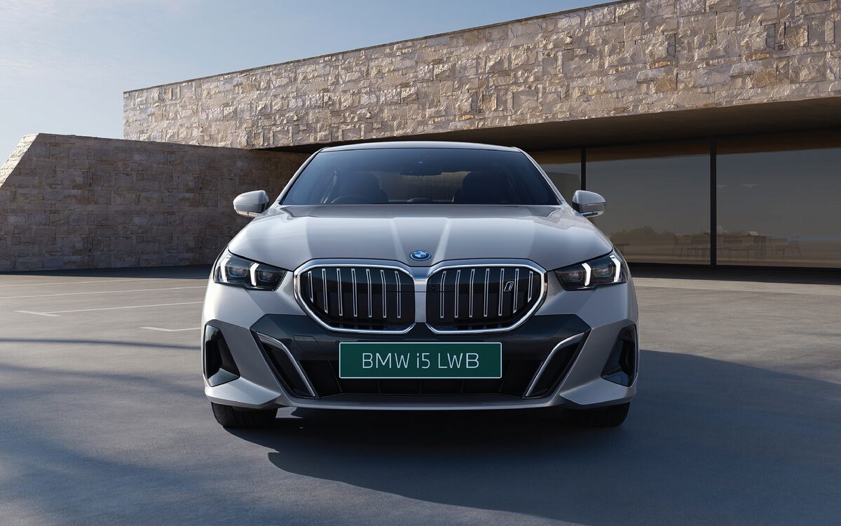 BMW i5 LWB in silver seen head-on in front of a stone building