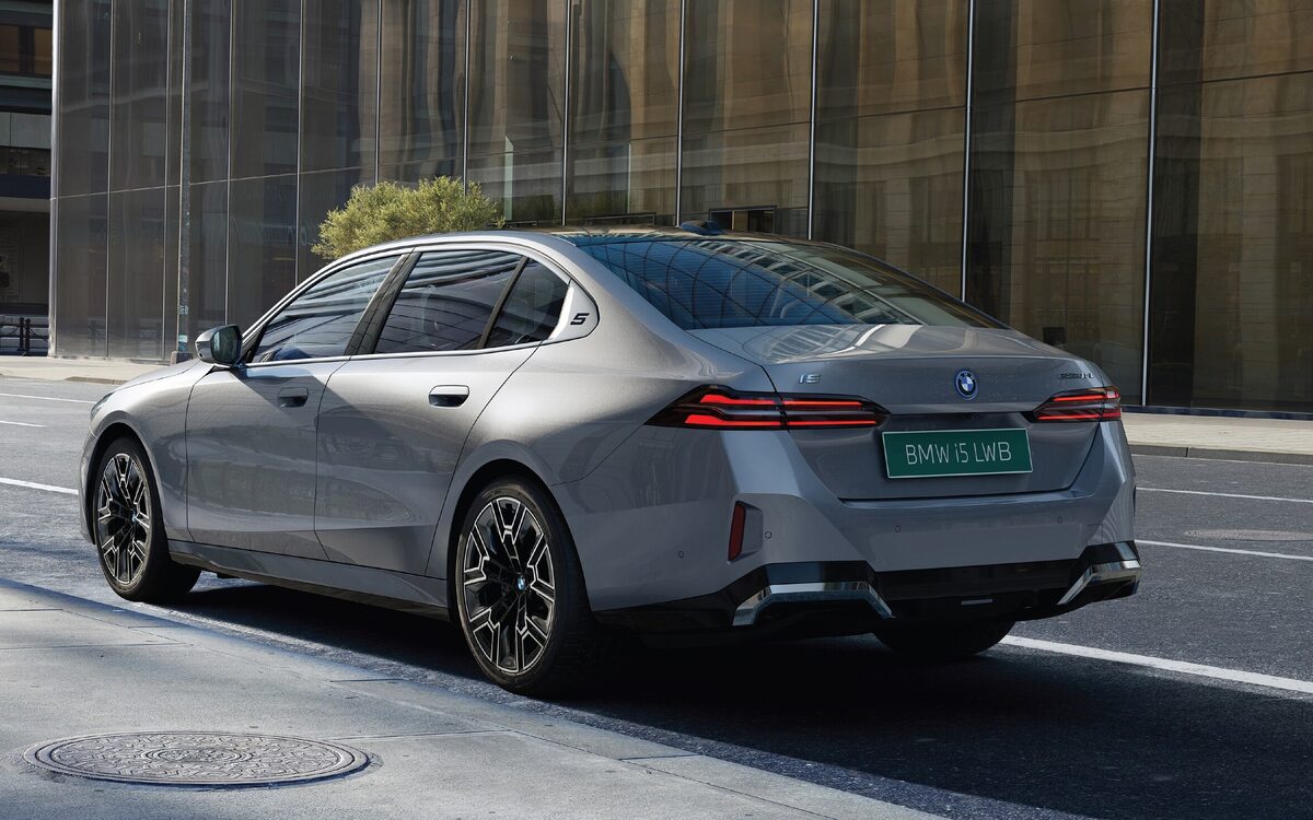 BMW i5 LWB rear three-quarter view on a city street, showing the LED tail lamps