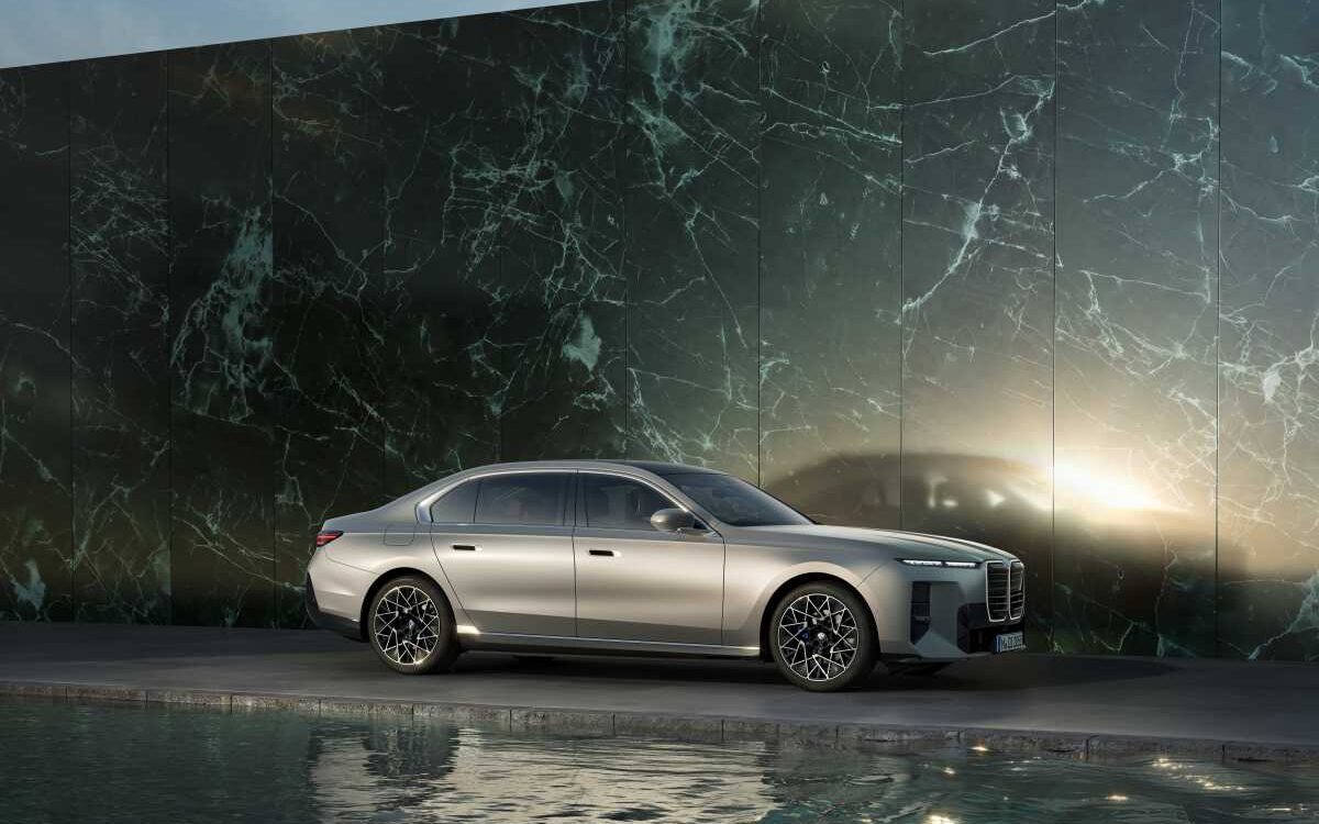 BMW i7 in silver, side profile by a dark marble wall with reflections