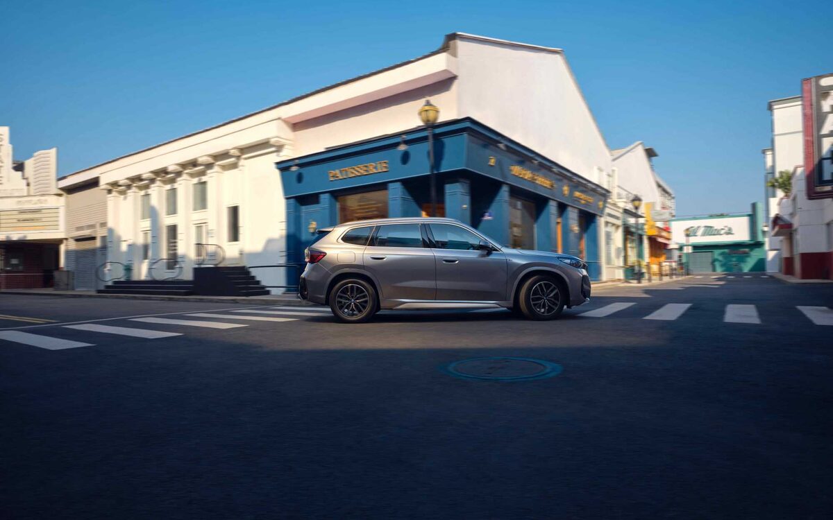 BMW iX1 LWB in grey, side profile on a city street