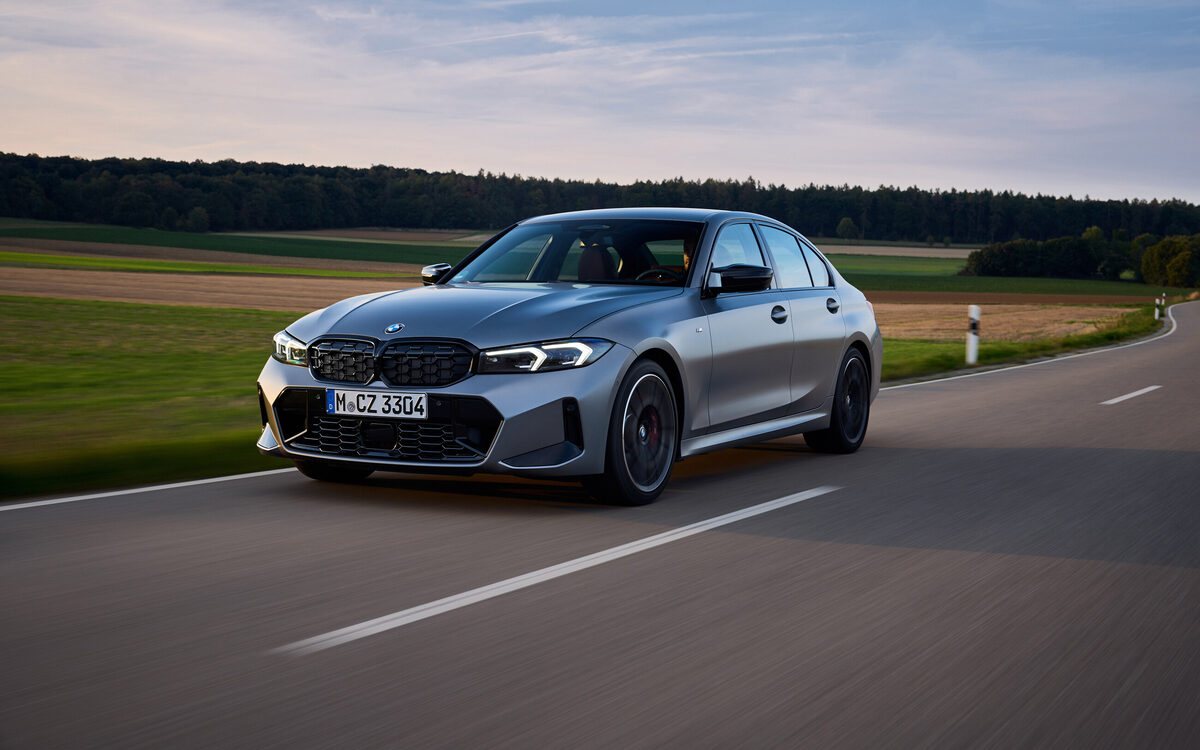 BMW M340i xDrive in grey driving on a country road, front three-quarter view