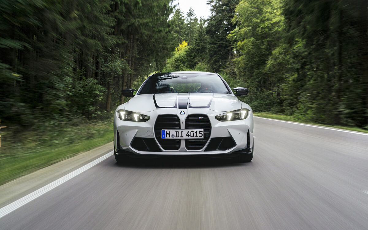 BMW M4 Competition driving on a forest road, front view