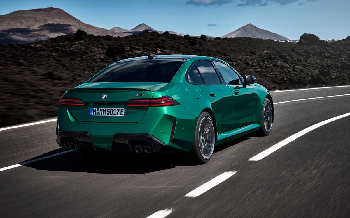 BMW M5 in green on a mountain road, rear three-quarter view