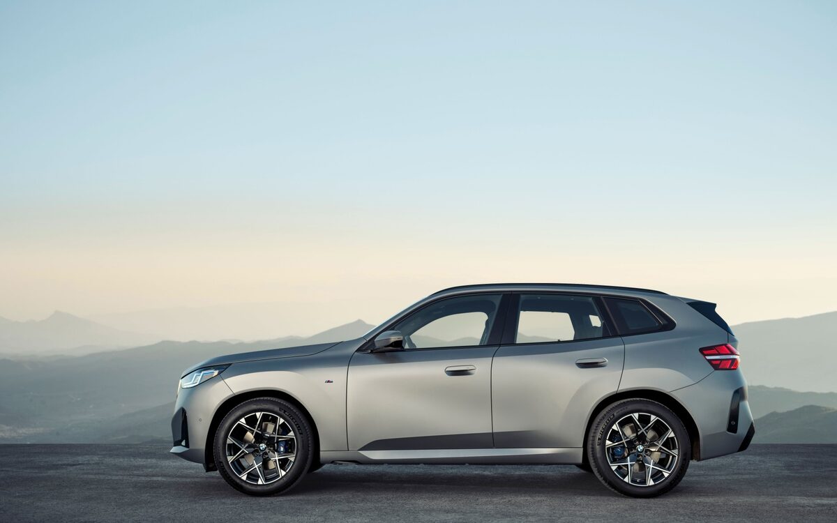BMW X3 in grey paint in side profile against a hazy mountain horizon