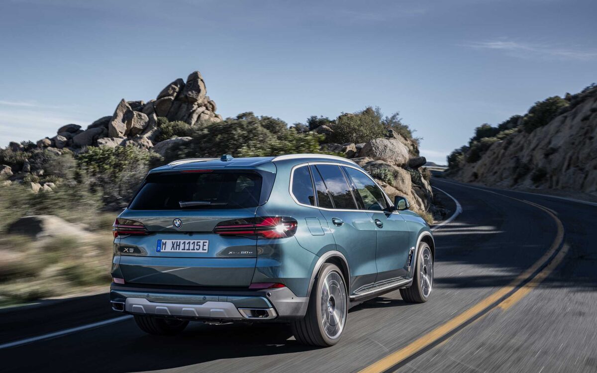 BMW X5 in blue on a winding road, rear three-quarter view