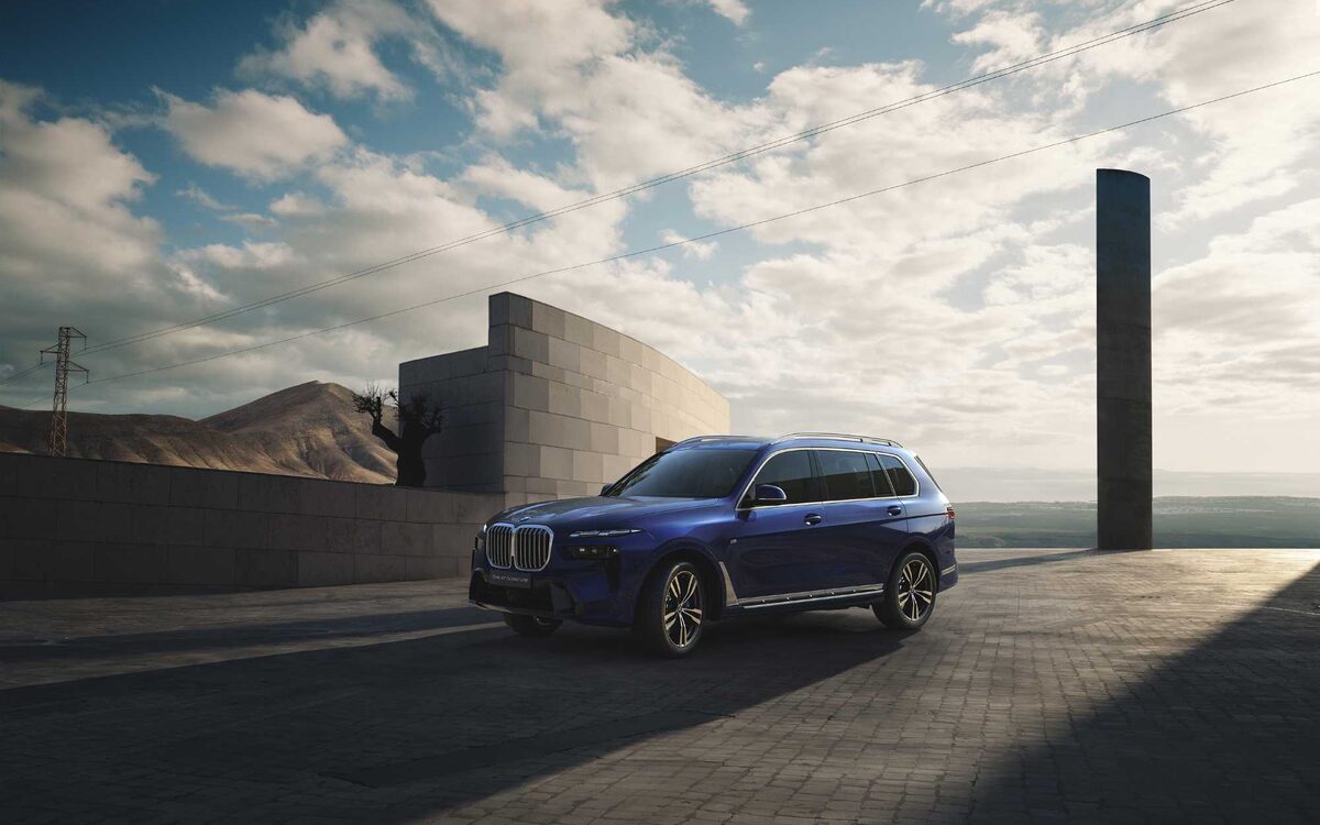 BMW X7 in Tanzanite Blue, front three-quarter view in a desert setting