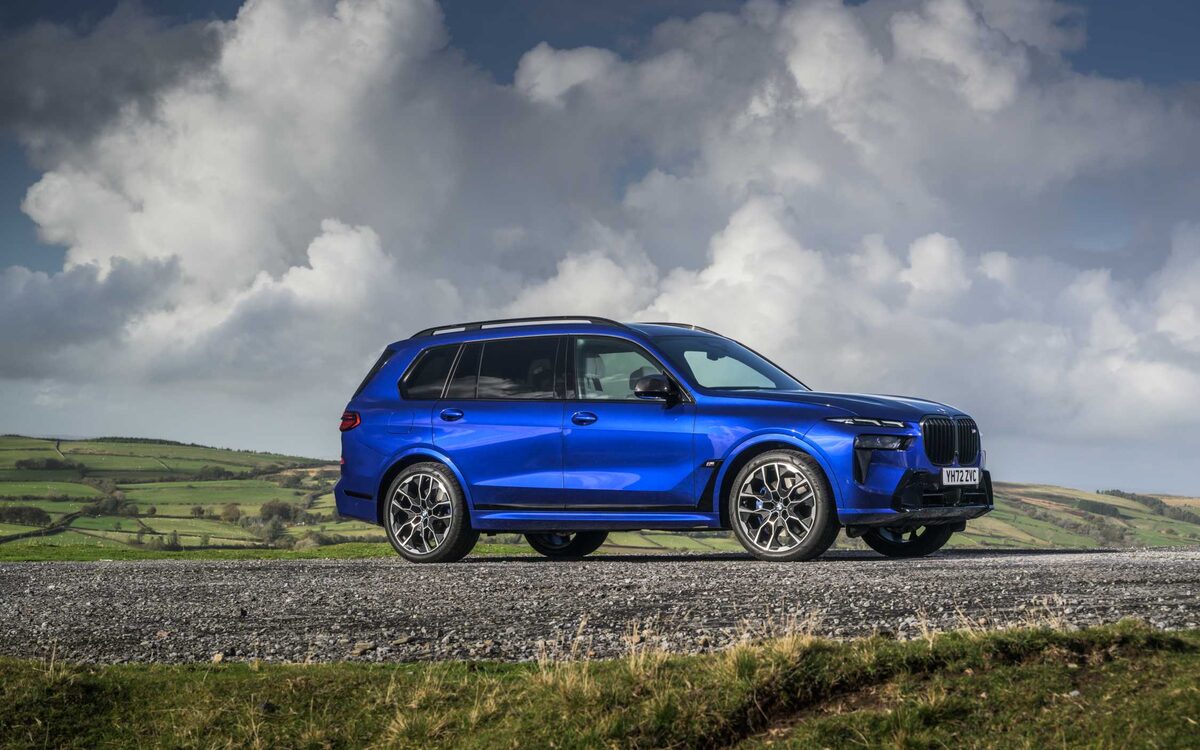 BMW X7 in blue parked on a hilltop, side profile