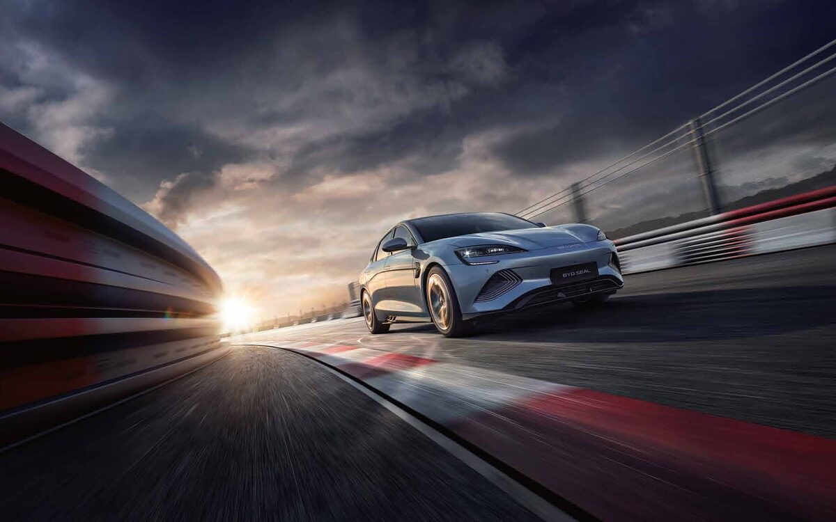 BYD Seal in blue-grey driving fast on a race track at sunset
