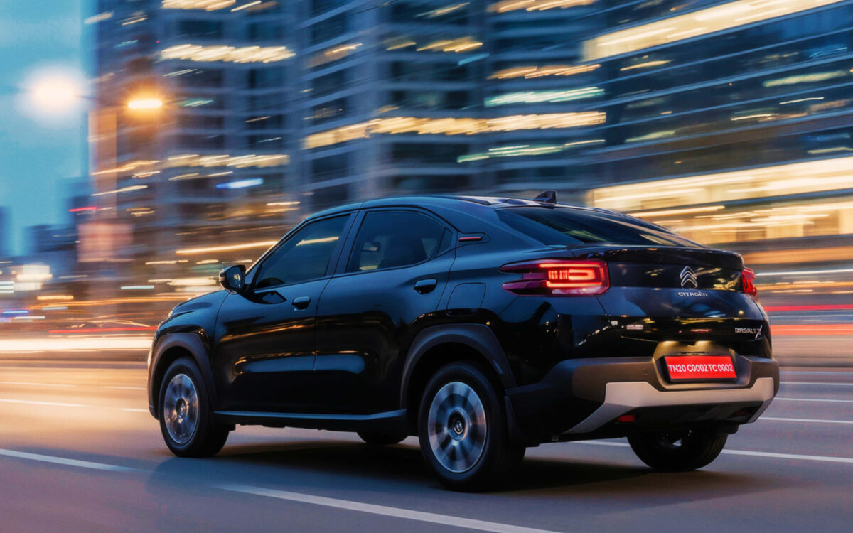 Citroen Basalt in black, rear three-quarter view driving past city lights