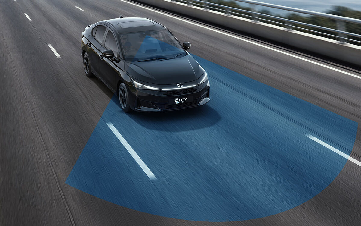 Black Honda City e:HEV driving on an elevated road, seen from the front three-quarter with a blue lane-keeping graphic