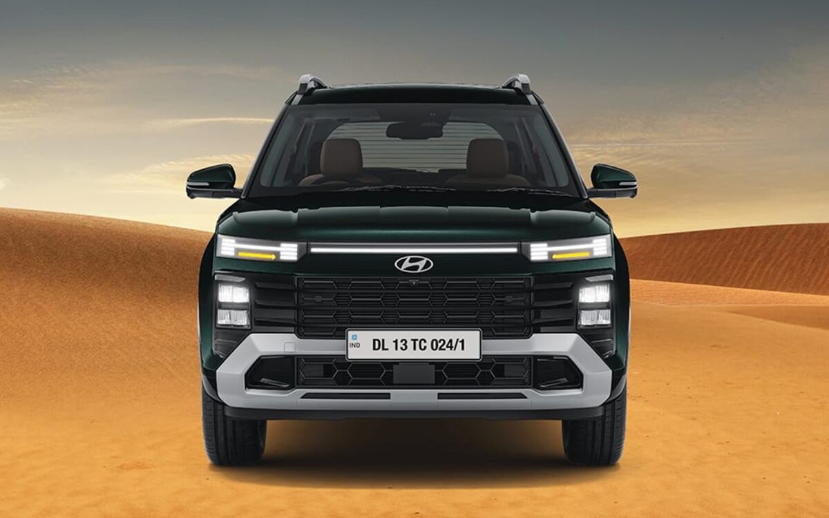 Hyundai Alcazar in black seen head-on on a desert track, showing the grille and light bar