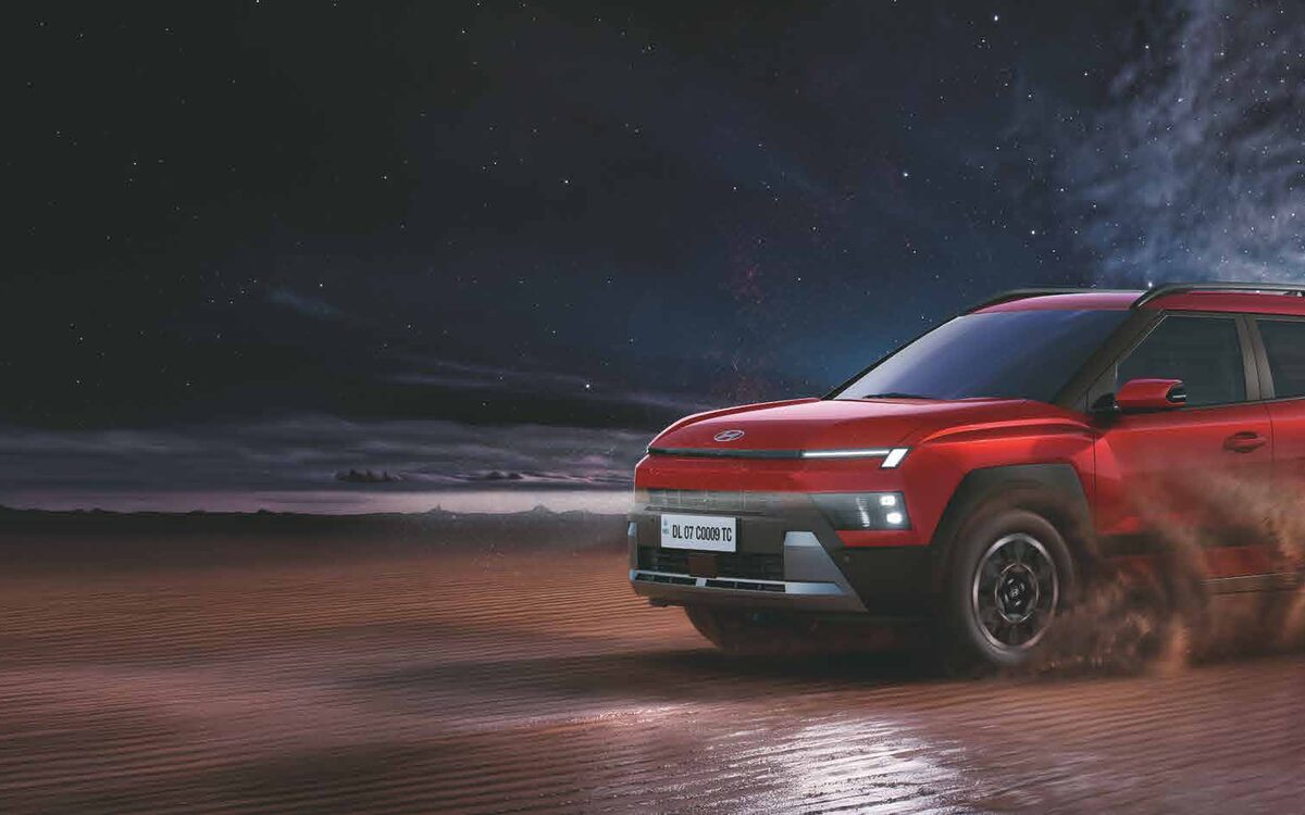 Hyundai Bayon in Fiery Red driving through desert sand at dusk