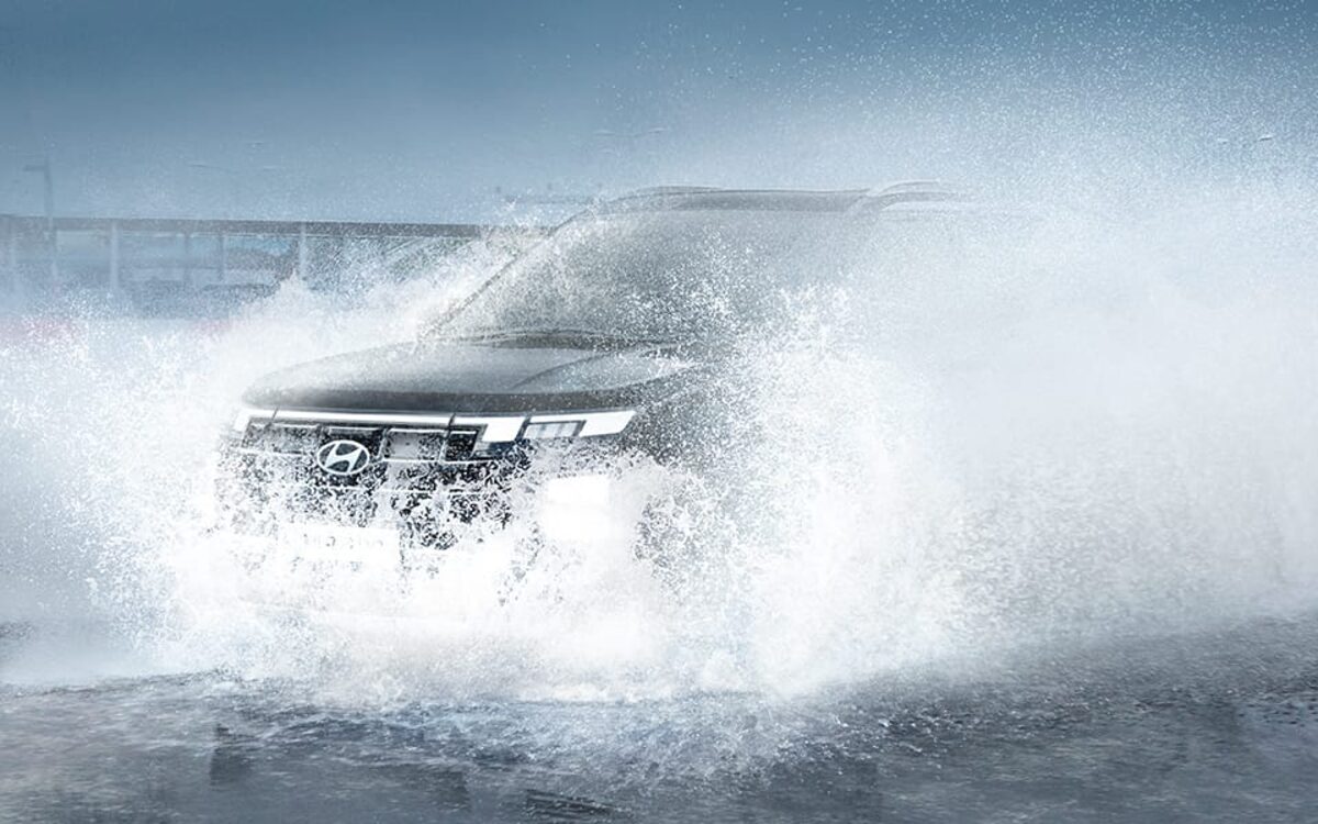 Hyundai Creta driving through a large water splash on a wet road