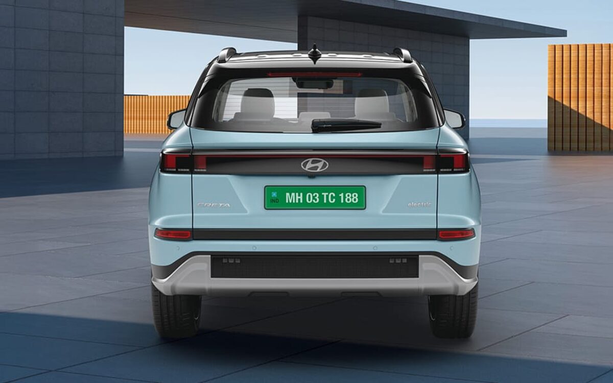 Hyundai Creta Electric in light blue, straight rear view in front of a modern building