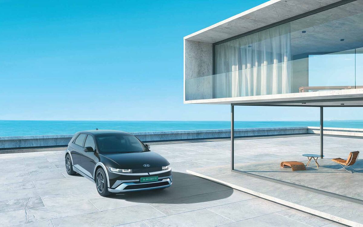 Hyundai IONIQ 5 in dark grey, front three-quarter view on a sunny sea-facing terrace