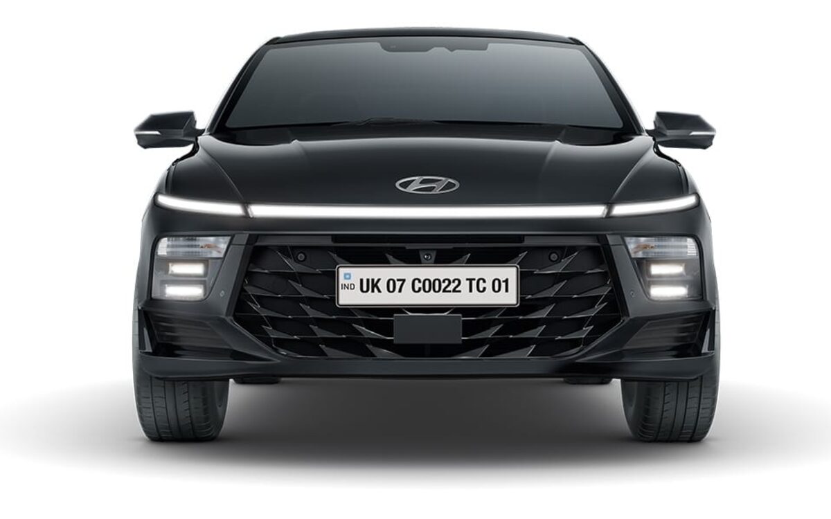 Hyundai Verna in black seen head-on, showing the full-width light bar and grille on a white background