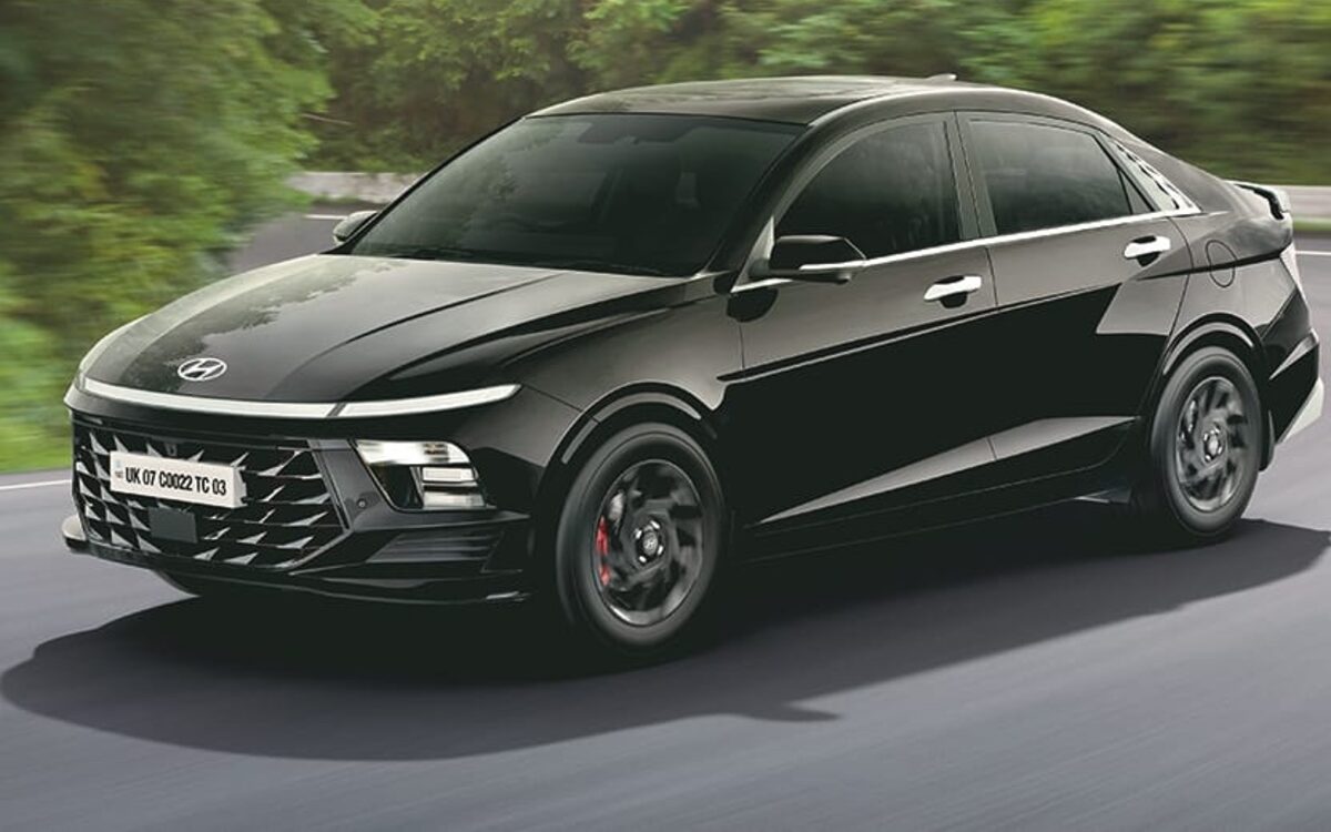 Hyundai Verna in black driving round a curve on a tree-lined road