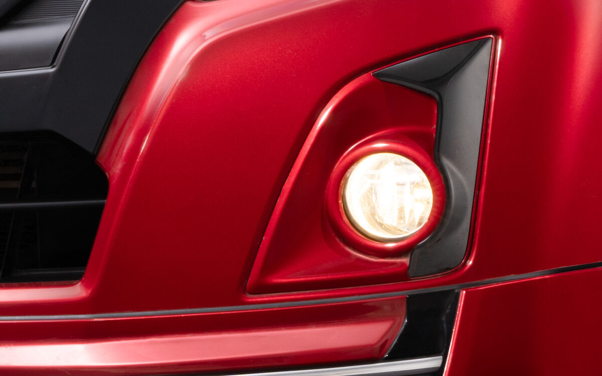 Close-up of the glossy black fog lamp bezel on a red Isuzu D-MAX V-Cross