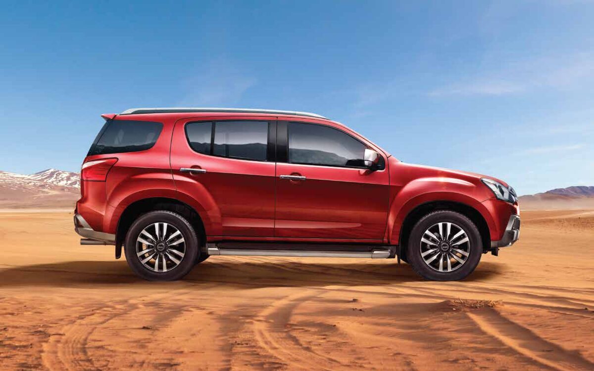 Red Isuzu mu-X in side profile on a desert sand track