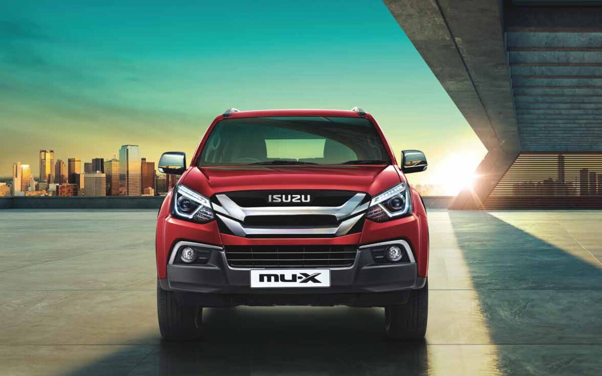Red Isuzu mu-X head-on with a city skyline in the background