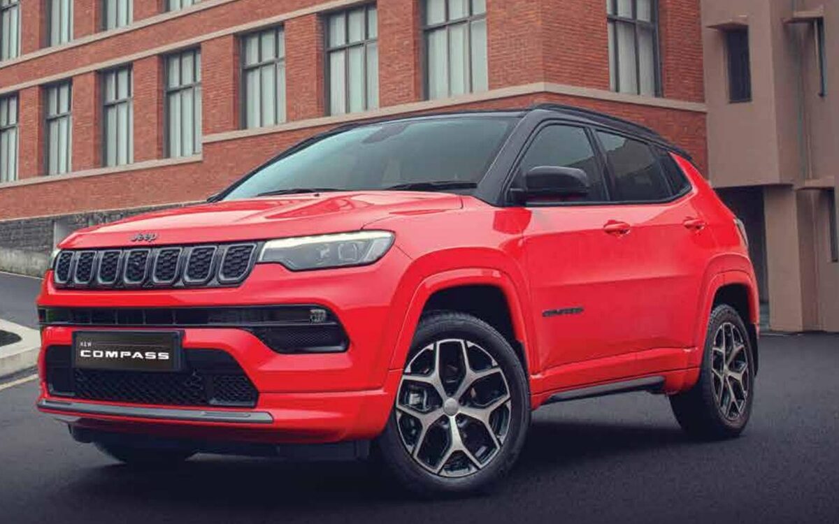 Jeep Compass in red with a black roof, front three-quarter view outside a brick building