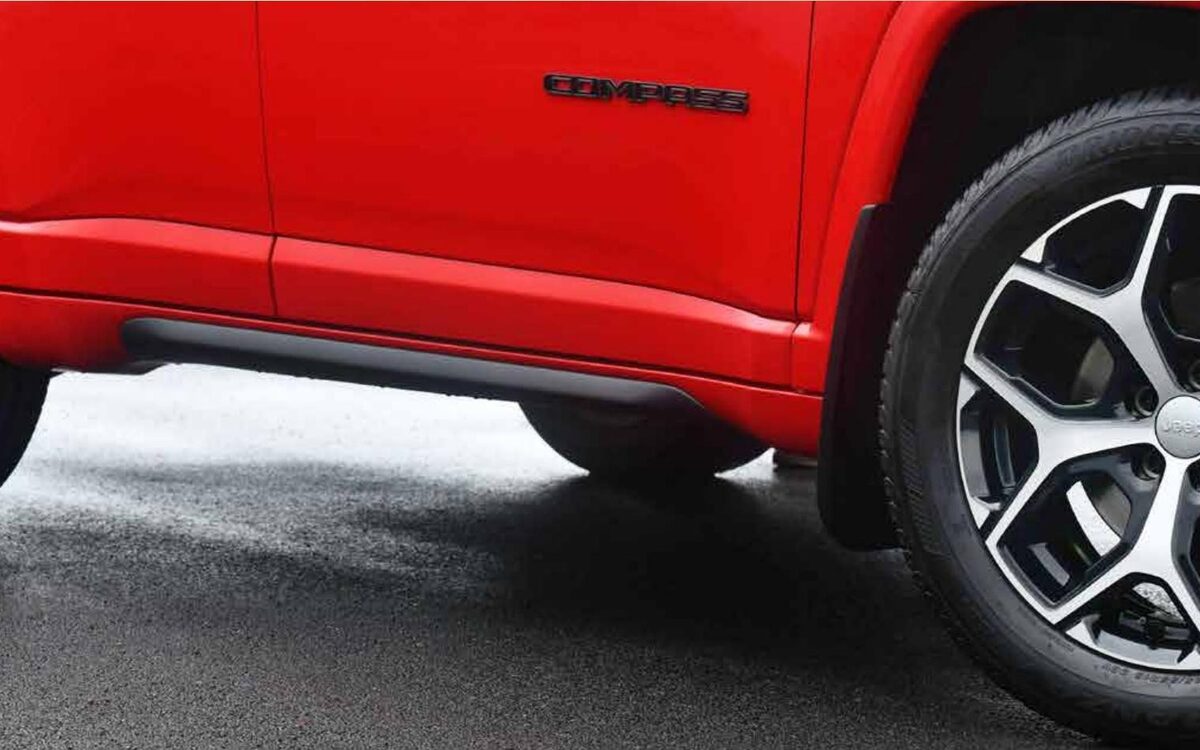 Close-up of the diamond-cut alloy wheel and body side of a red Jeep Compass