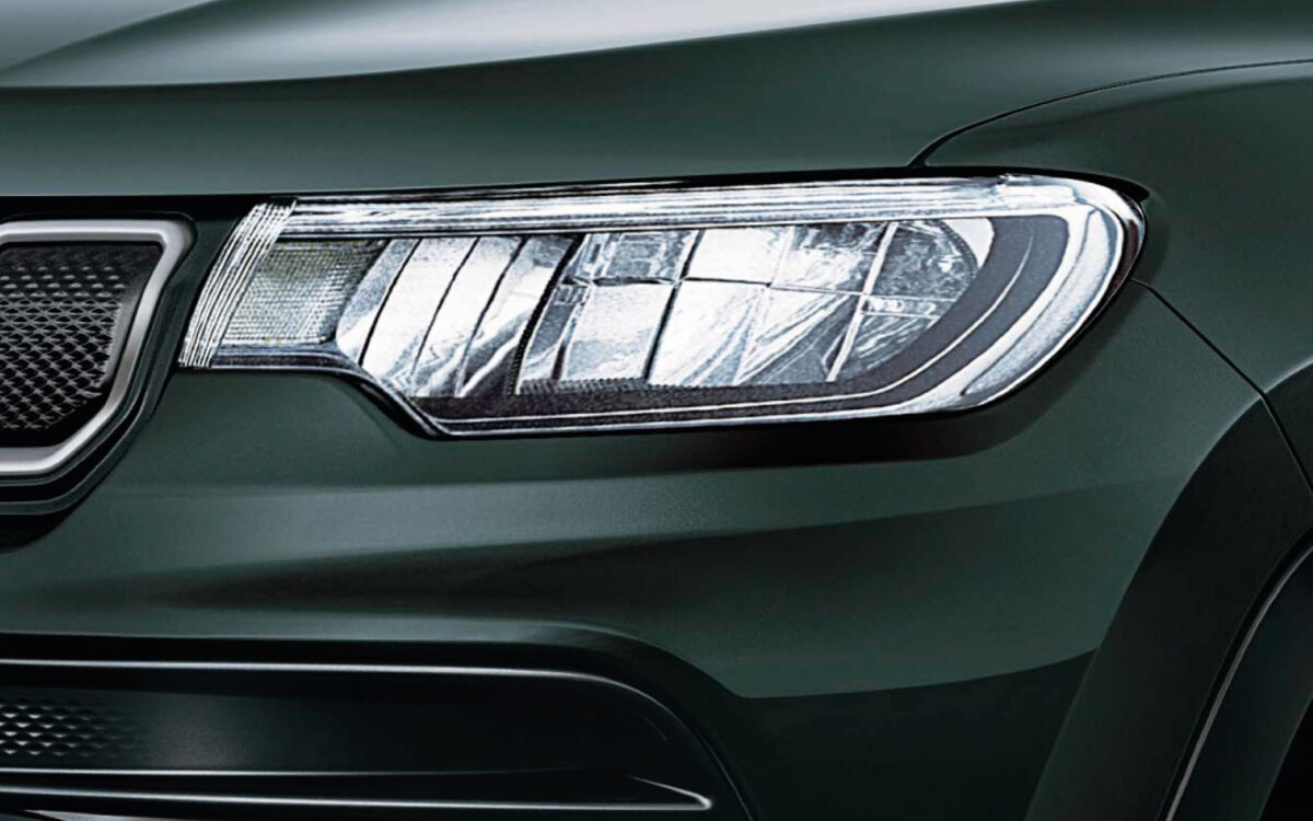 Close-up of the LED headlamp on a dark green Jeep Compass