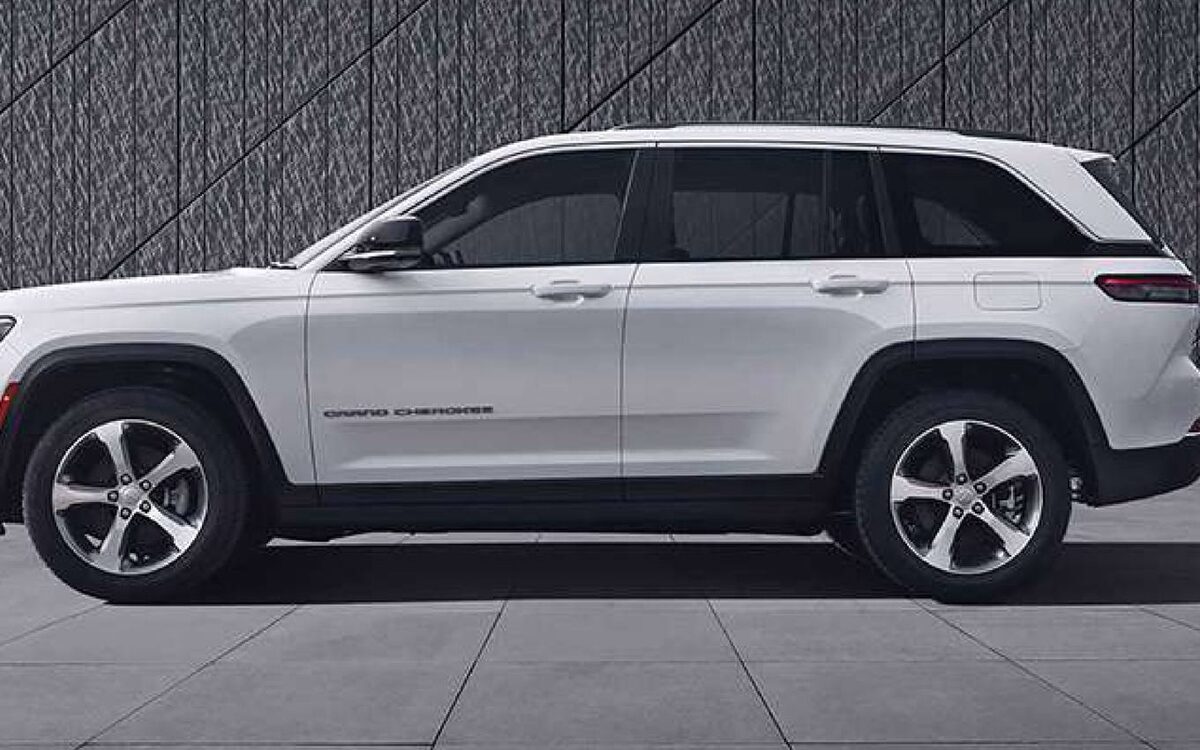 White Jeep Grand Cherokee in side profile against a dark textured wall