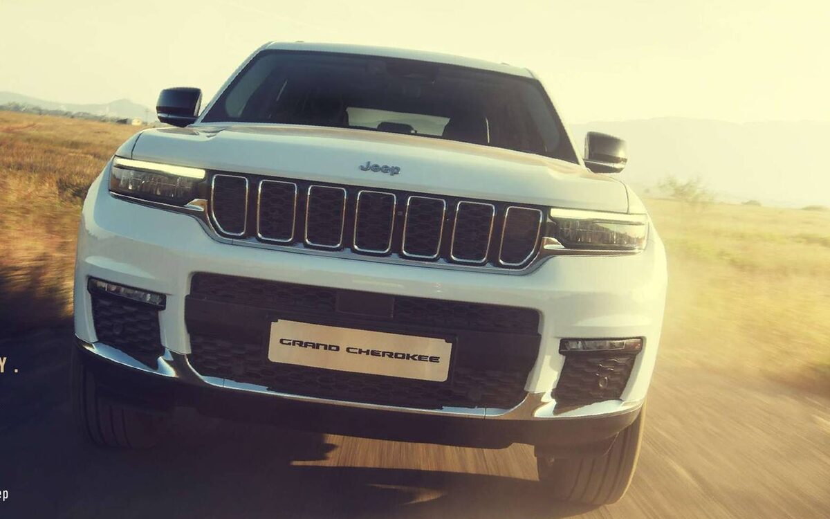 White Jeep Grand Cherokee driving towards the camera on a dusty trail